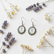 Lavender floral cabochon drop earrings flat lay with dried lavender and wildflowers on white linen