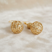 Gold filigree cage bead drop earrings styled on cream fabric