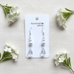 Sterling silver pearl and crystal teardrop earrings flat lay on white linen with flowers