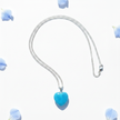 Turquoise blue glass heart pendant necklace flat lay with blue flower petals on white background