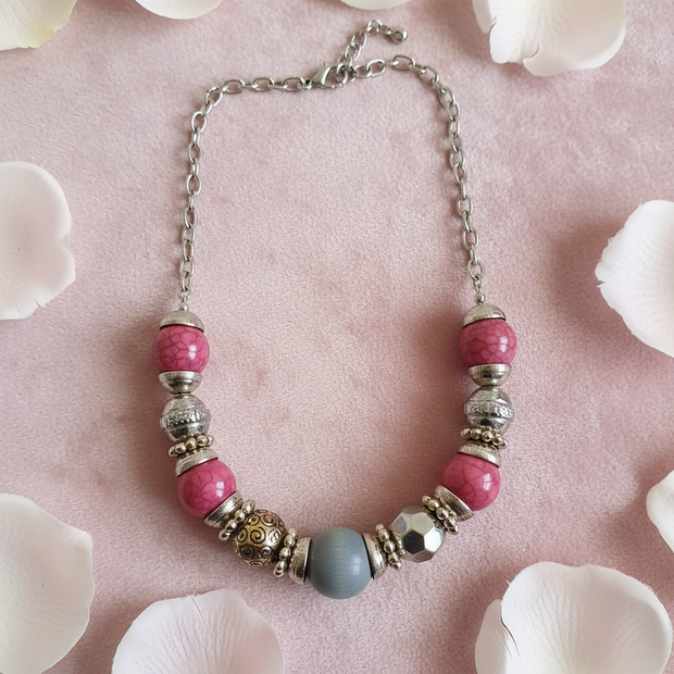 Rescued & Remade pink crackle bead necklace flat lay on blush pink velvet with rose petals