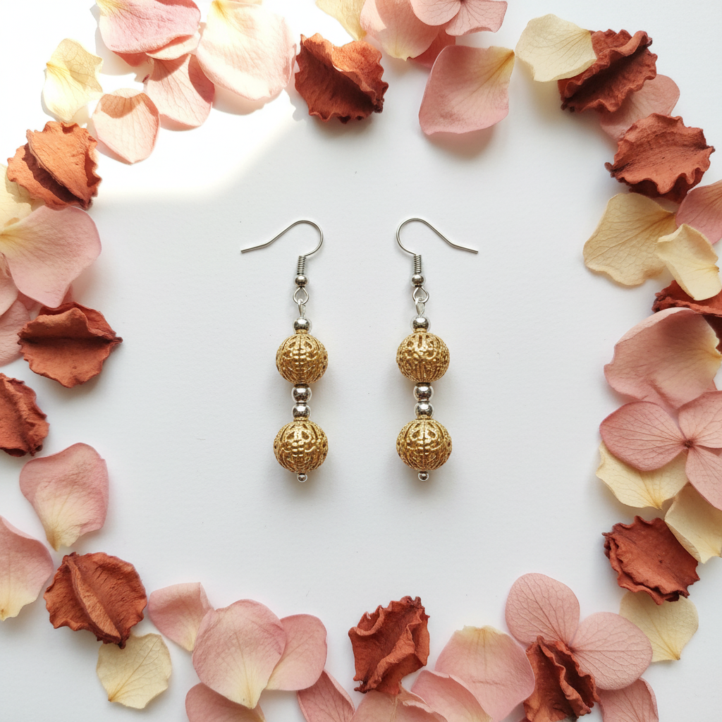 Gold filigree double cage bead drop earrings flat lay with flower petals