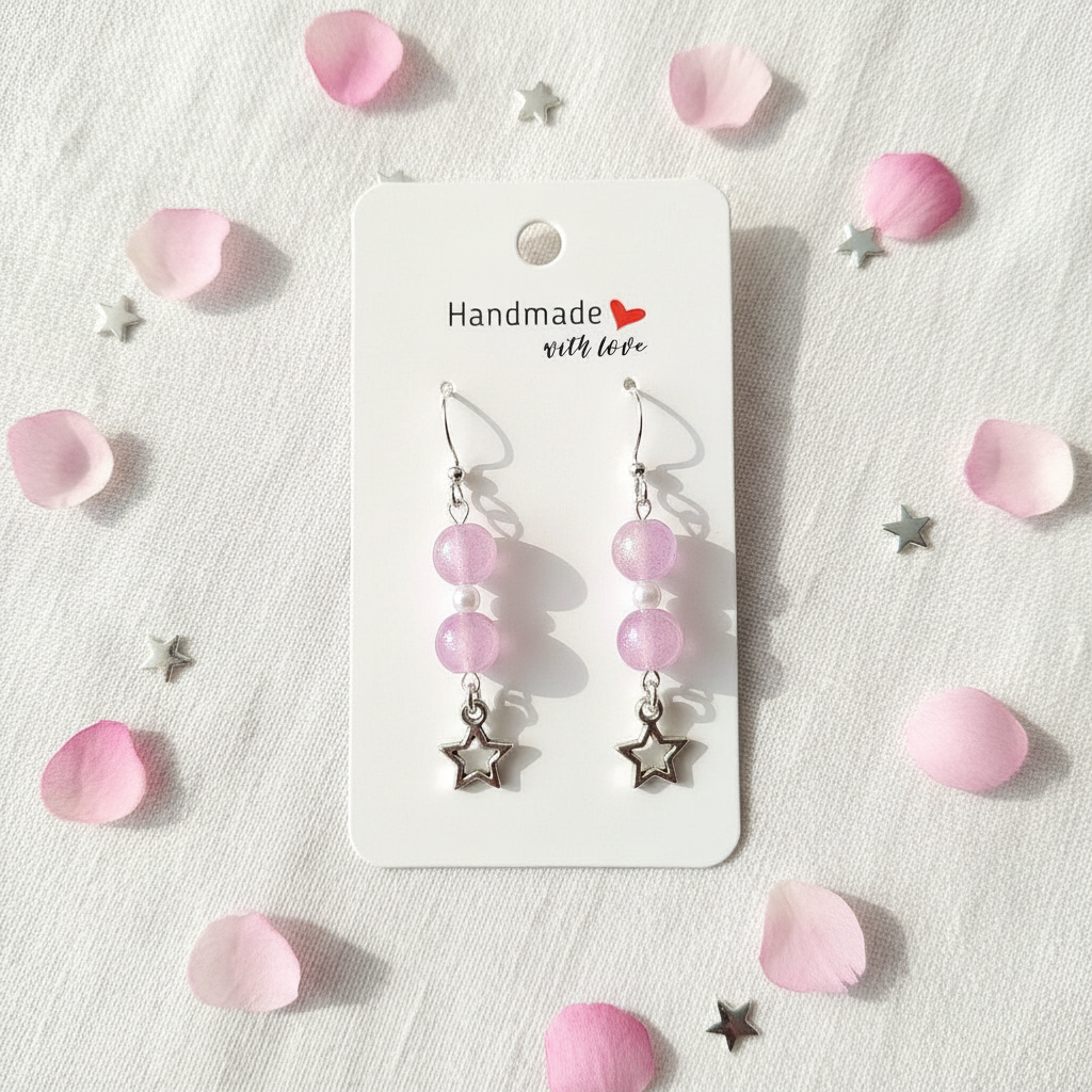 Pink bead and silver star charm sterling silver earrings flat lay on white linen with pink petals