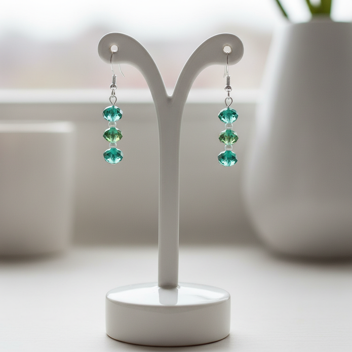 Green and white sterling silver earrings displayed on white ceramic jewellery stand