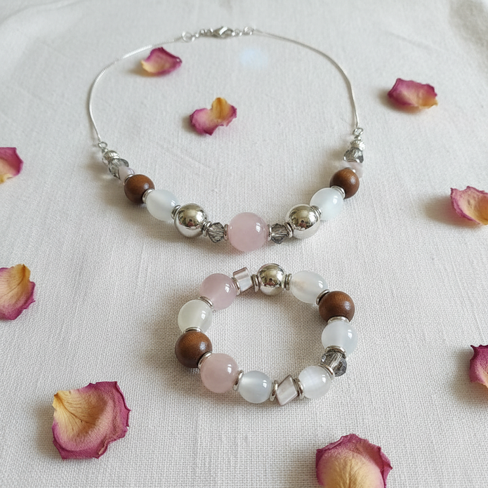 Rescued & Remade rose quartz and wood bead necklace and bracelet set flat lay on white linen with dried rose petals