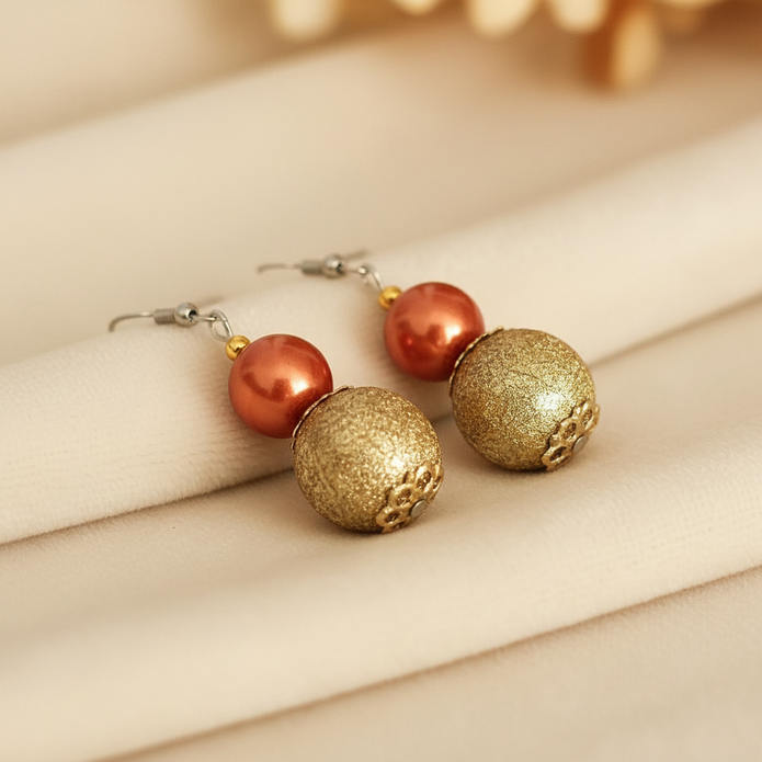 Copper pearl and gold textured bead drop earrings styled on cream fabric