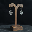 Silver plated pentacle drop earrings displayed on a rustic wooden earring holder