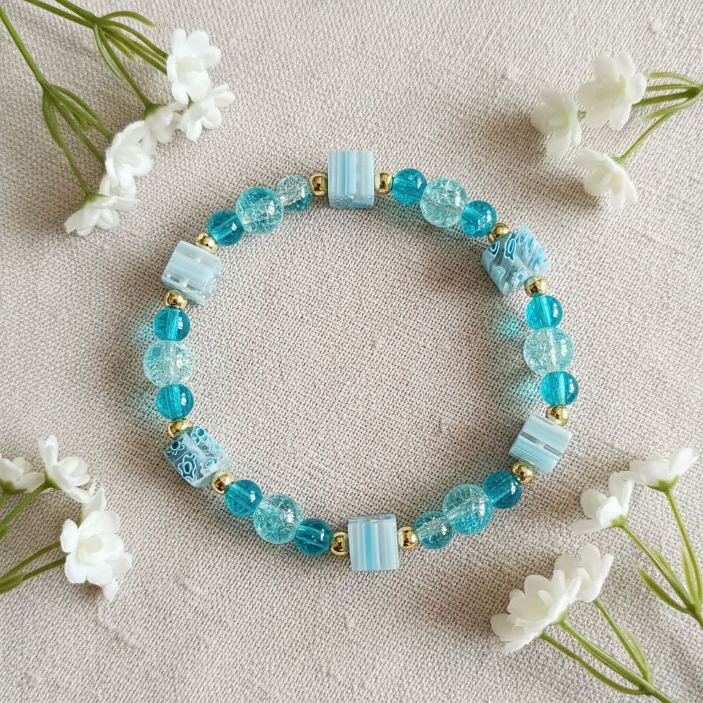 Teal crackle bead bracelet flat lay with white flowers on linen