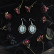 Gothic flat lay of iridescent blue holographic cabochon earrings on dark velvet