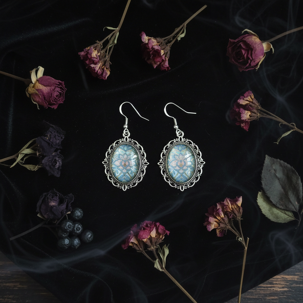 Gothic flat lay of iridescent blue holographic cabochon earrings on dark velvet