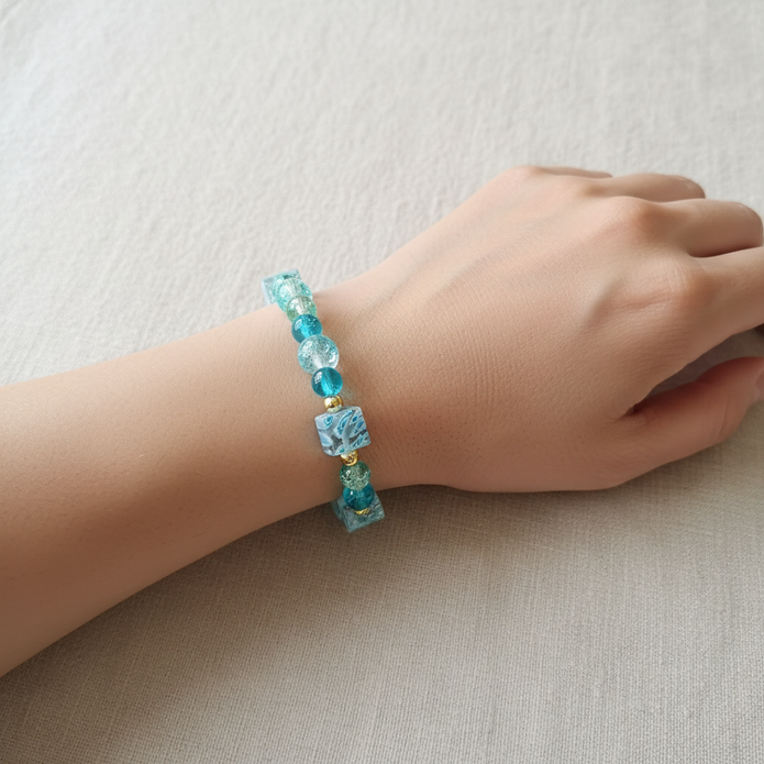 Teal and ice blue crackle bead bracelet worn on a model's wrist