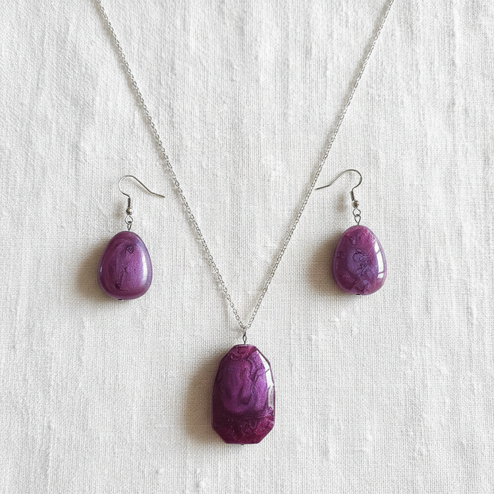 Flat lay of purple stone necklace and matching earrings on white linen