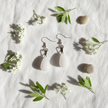 White quartz teardrop earrings lifestyle flat lay with white flowers and green leaves